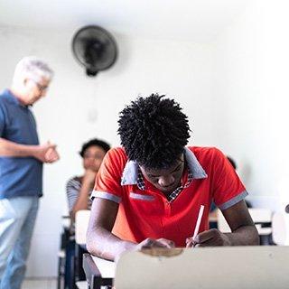 Students sit and take tests while a proctor observes